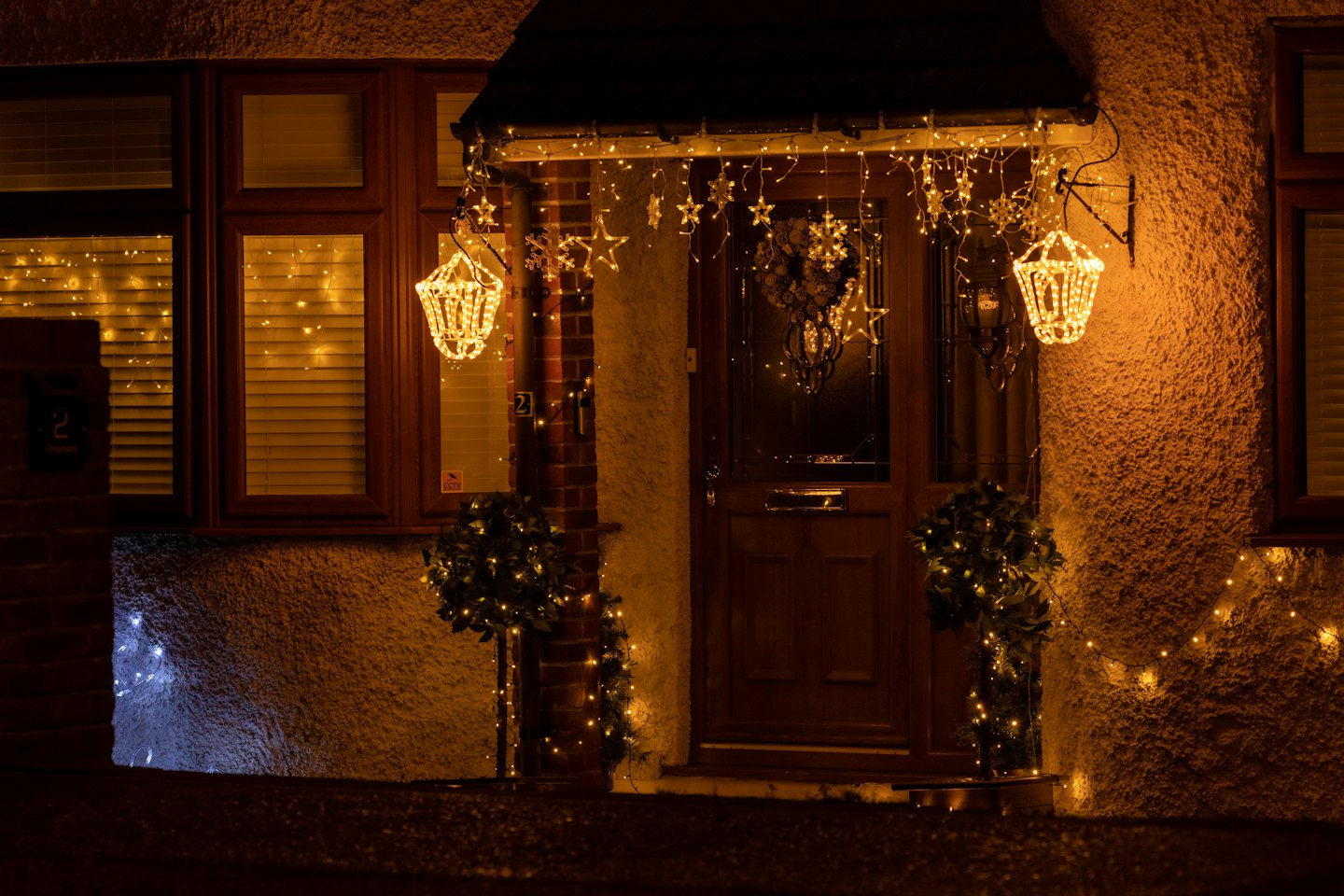 Residential house decorated with warm yellow Christmas lights at night.