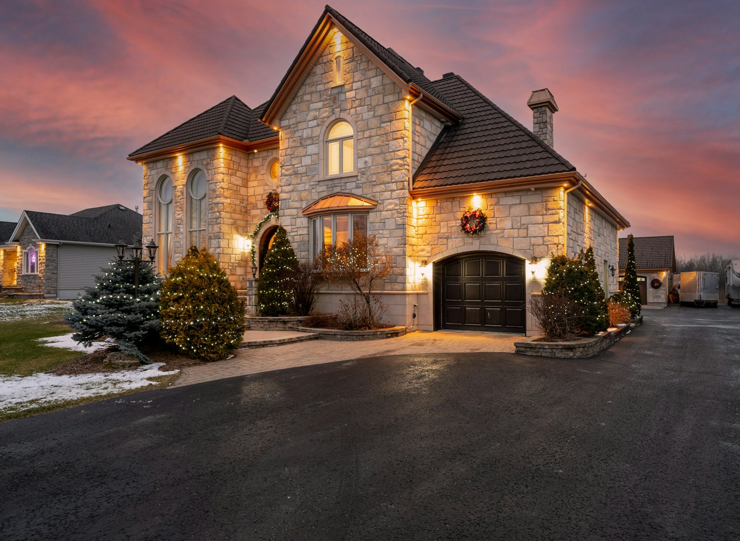 Stone house decorated for the holidays during a winter sunset.